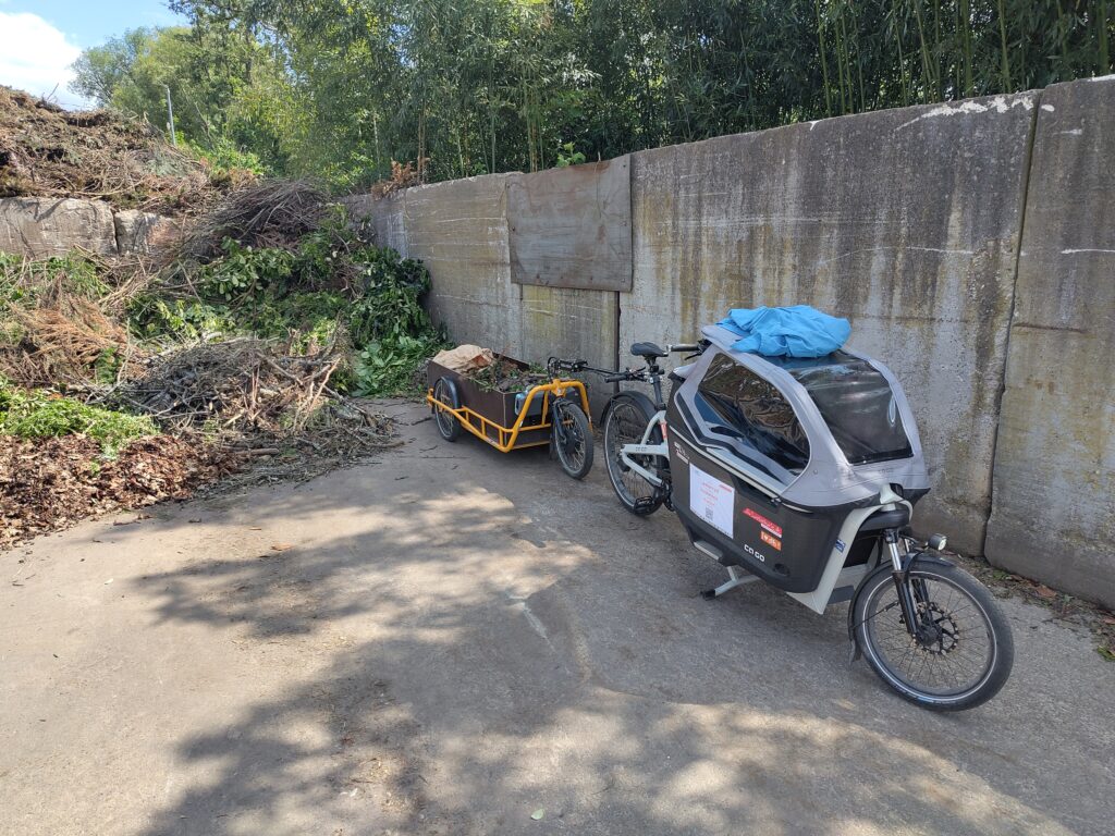 Das Lastenrad mit dem Anhänger steht mit Ladung in der Grünschnittanlage.