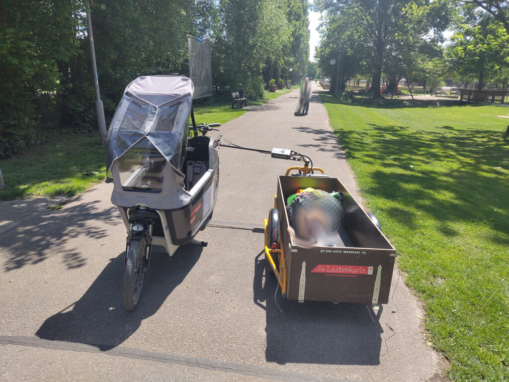 Auf einem Parkweg steht das Lastenrad um 180° entgegen dem Anhänger.